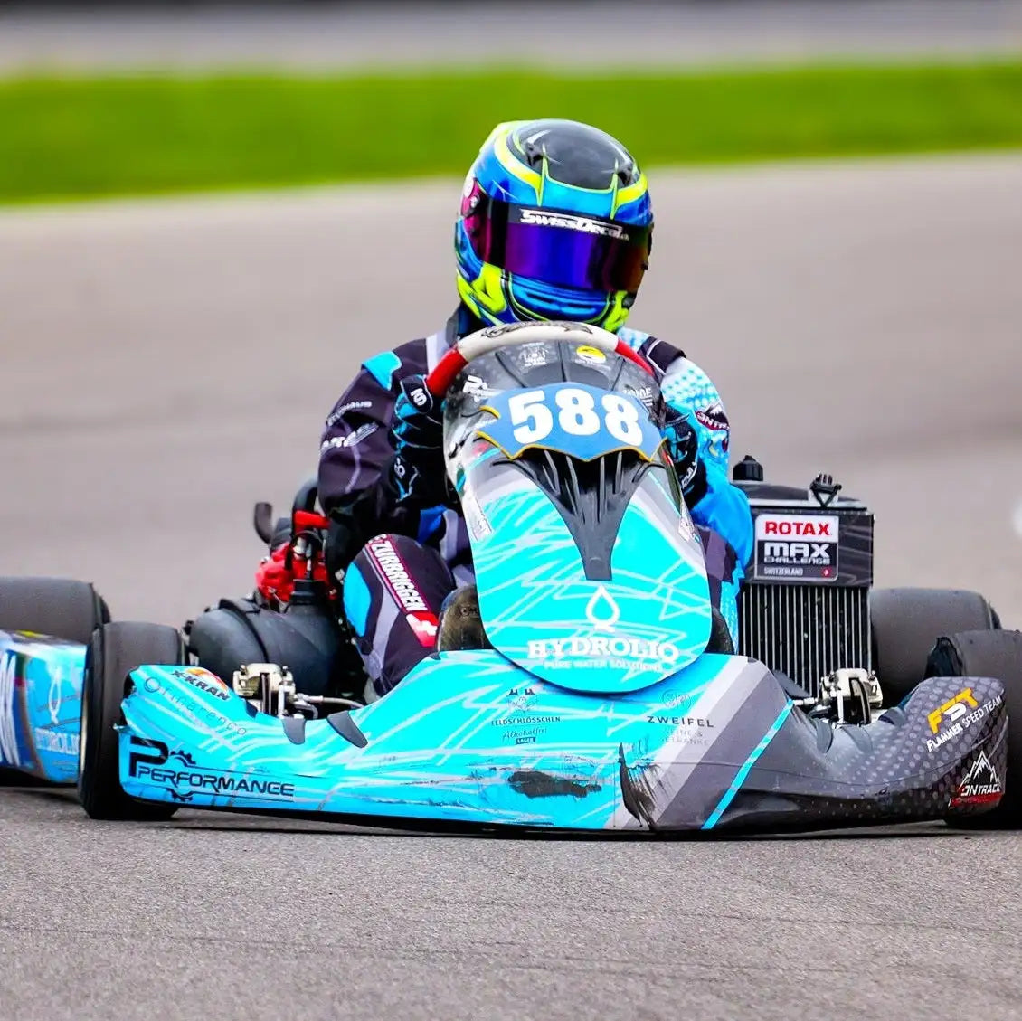 Ein lebendiger türkisfarbener und schwarzer Go-Kart mit Sponsorenaufklebern, mit einem schlanken aerodynamischen Design und der Rennnummer 588 an der Vorderseite.
