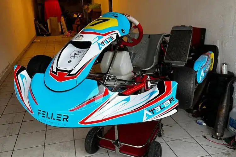 Ein leuchtend blaues, rotes und weißes Go-Kart mit „atelier“-Branding auf seinen Seitenverkleidungen.