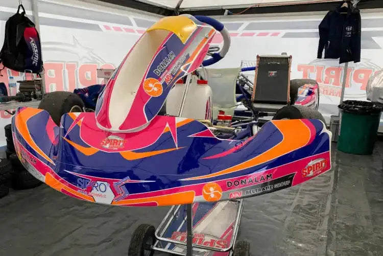 Leuchtendes blaues, oranges und pinkfarbenes Renn-Kart mit glänzender Oberfläche und Sponsoren-Aufklebern.