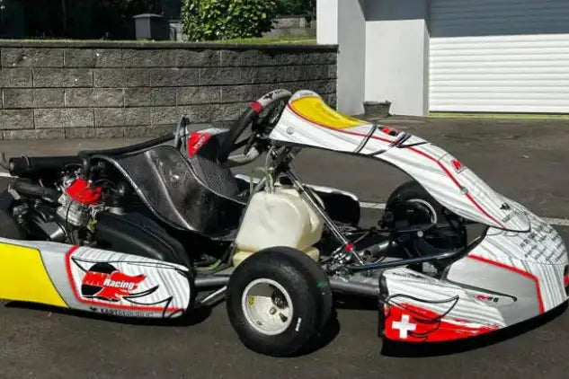 Weiße und gelbe Go-Kart mit roten Akzenten, mit Rennsport-Design und Schweizer Flaggenemblem vorne.